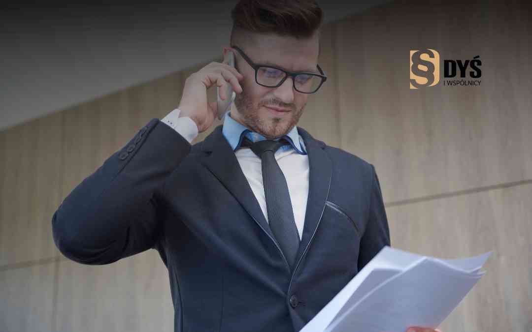 Przedsiębiorca z Lublina analizuje dokumenty podczas rozmowy telefonicznej przed biurowcem.