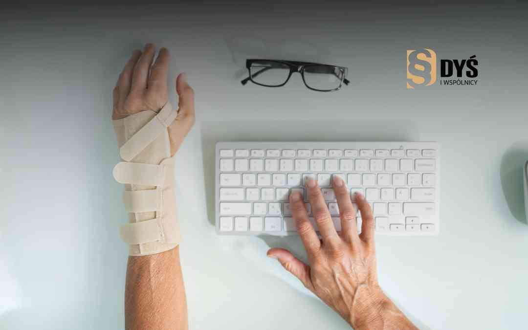 Osoba w stabilizującej ortezie nadgarstka pisze na białej klawiaturze komputera.