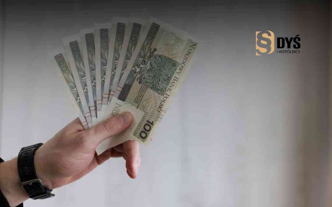 Mężczyzna trzyma wachlarz banknotów 100-złotowych – ilustracja odzyskania kosztów kredytu dzięki sankcji kredytu darmowego.
