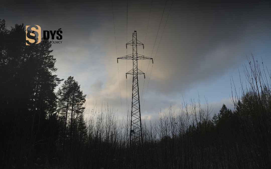 Słup na tle pochmurnego nieba jako przykład infrastruktury elektroenergetycznej na działce.