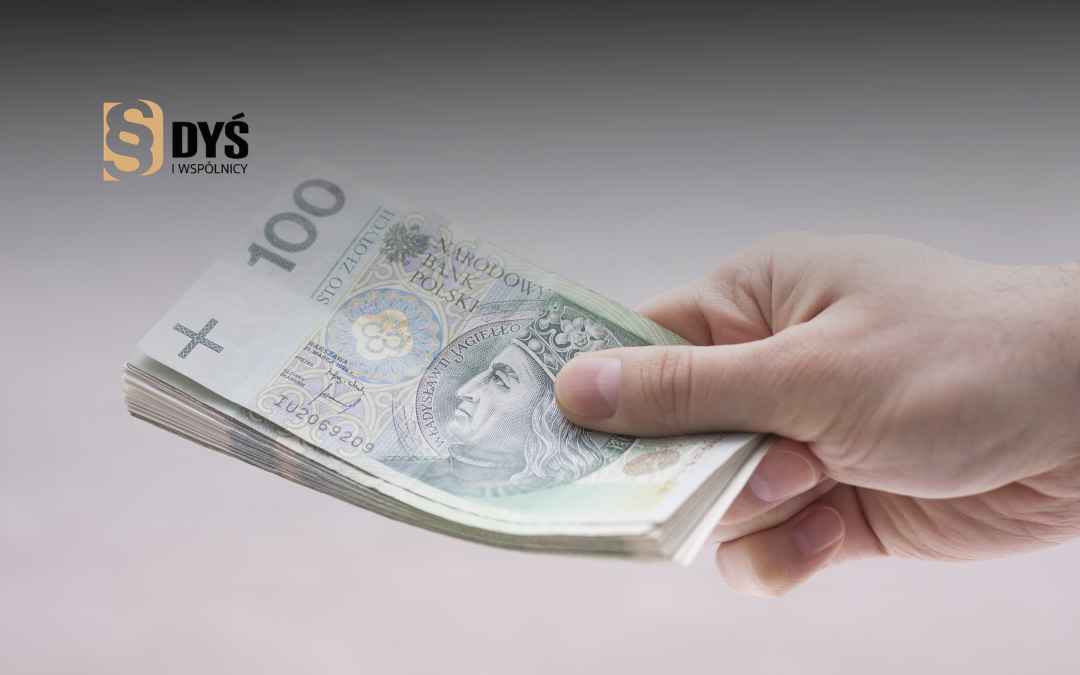 Ręka przekazująca plik polskich banknotów – ilustracja do wypłaty renty odszkodowawczej.
