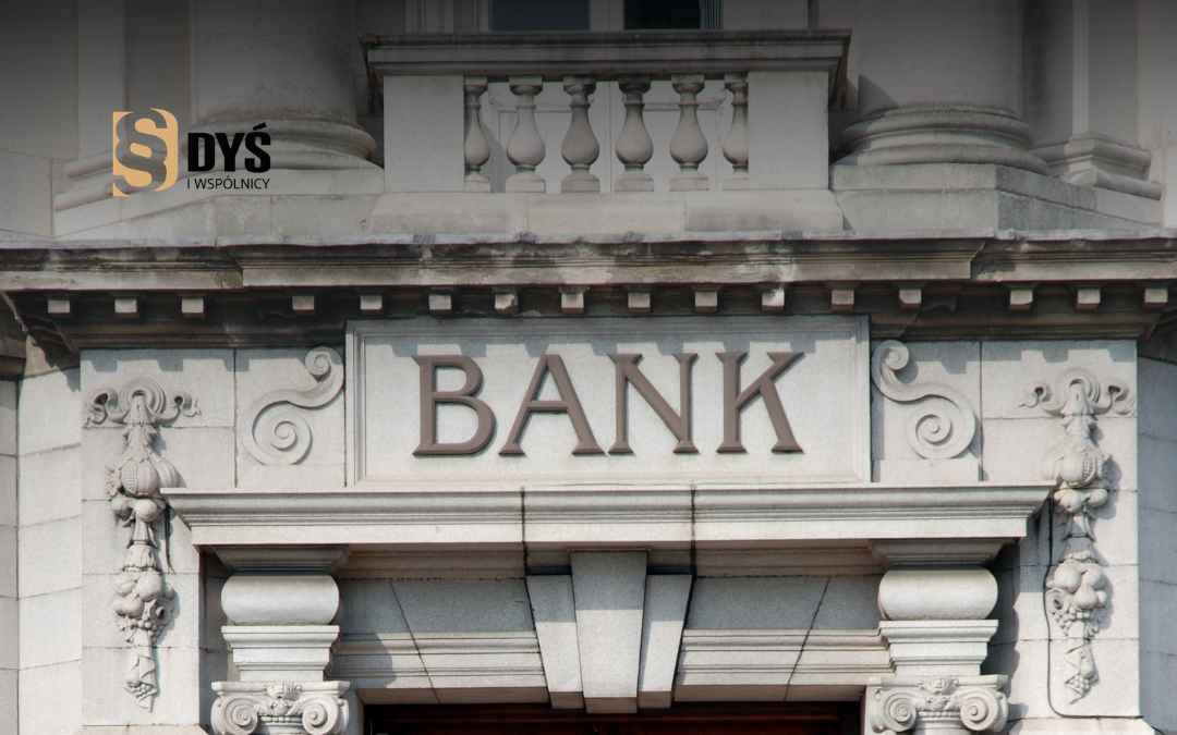 Kamienna elewacja budynku z napisem BANK nad wejściem głównym.