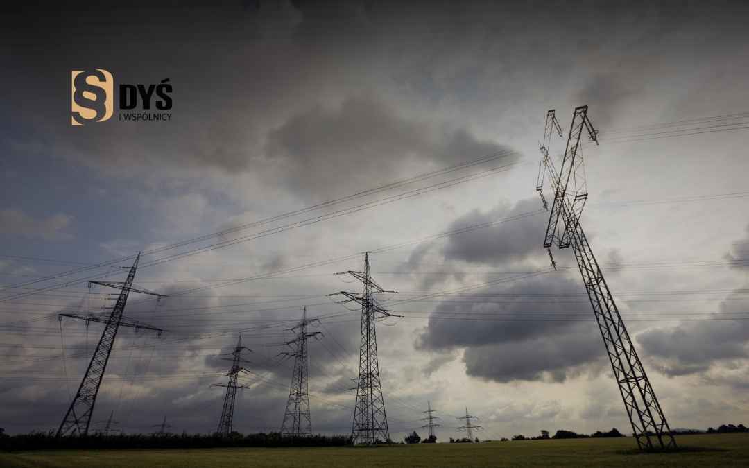 Słupy energetyczne wysokiego napięcia na tle zachmurzonego nieba – pas technologiczny na działce.