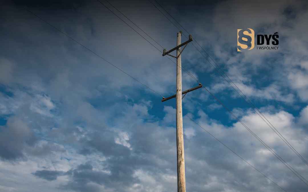 Stary drewniany słup z liniami energetycznymi na tle zachmurzonego nieba – uregulowanie stanu prawnego gruntu.