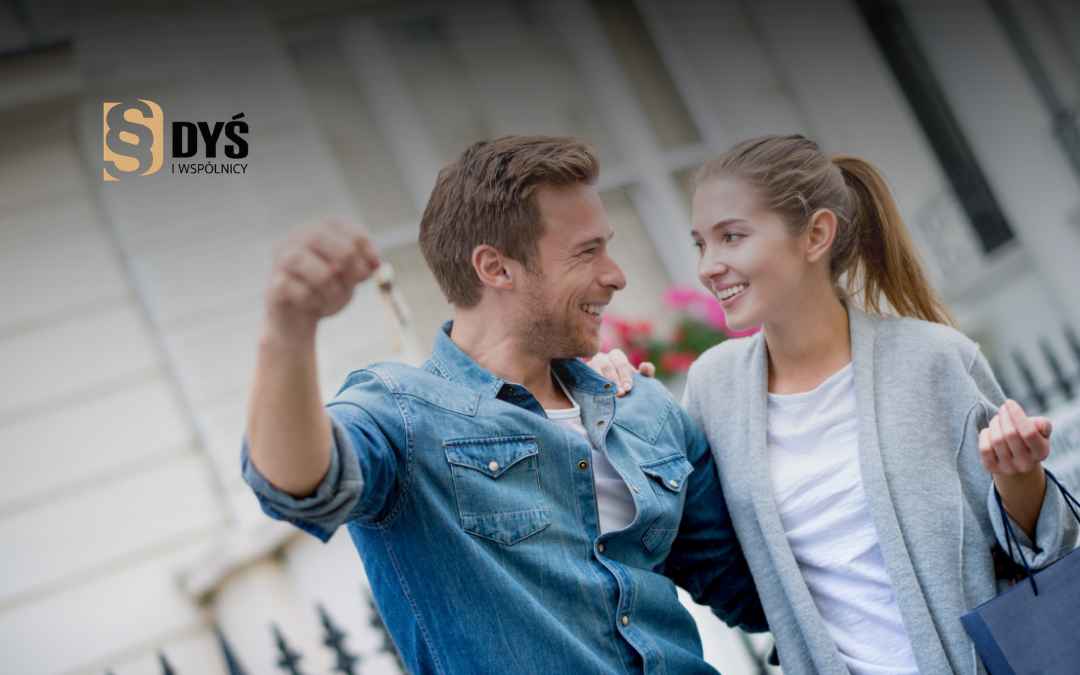 Uśmiechnięta para ciesząca się z zakupu nieruchomości i trzymająca klucze do nowego mieszkania.