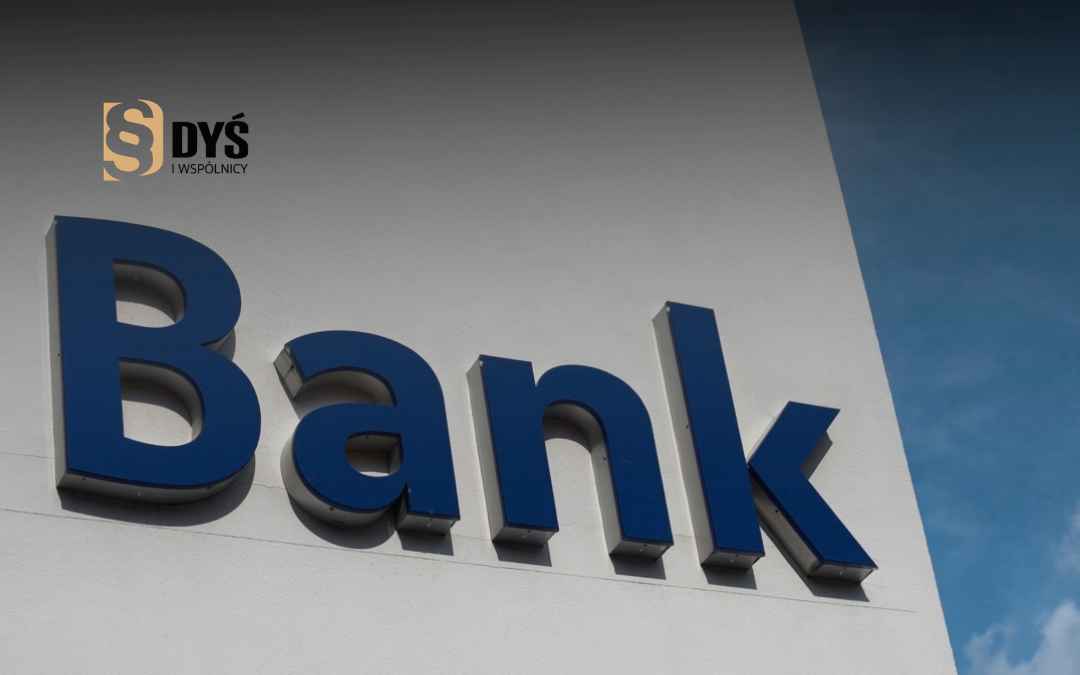 Granatowy, trójwymiarowy napis „Bank” na jasnej elewacji budynku – ilustracja do artykułu o kredytach hipotecznych.