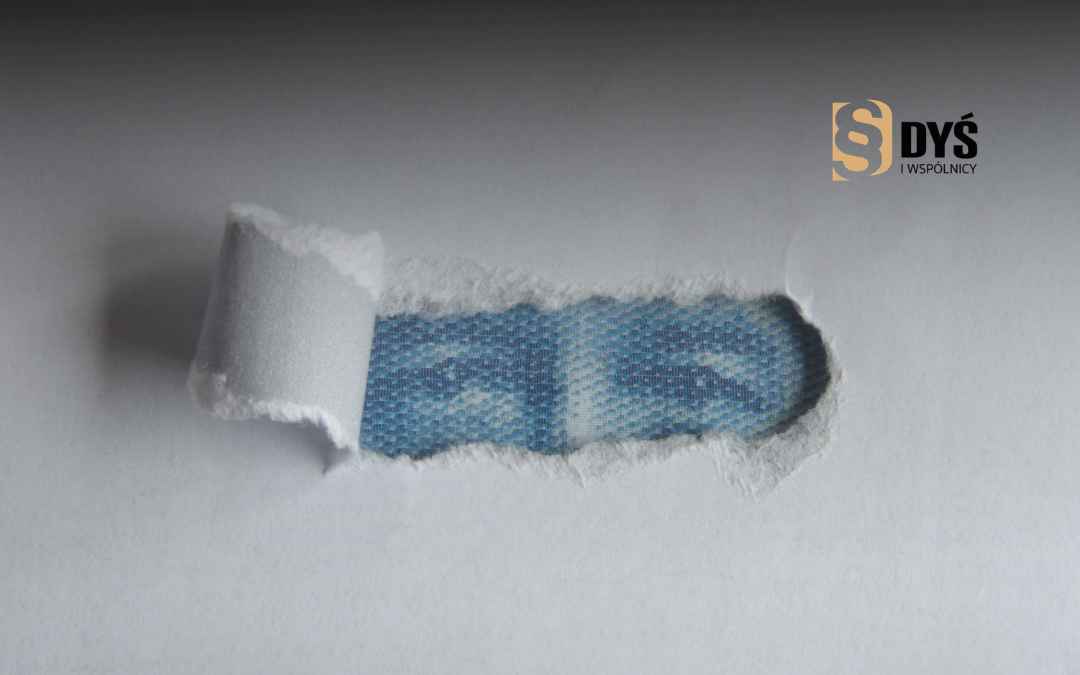 Naddarta biała kartka odsłaniająca fragment wzoru banknotu – symbol ukrytych klauzul abuzywnych w umowie.