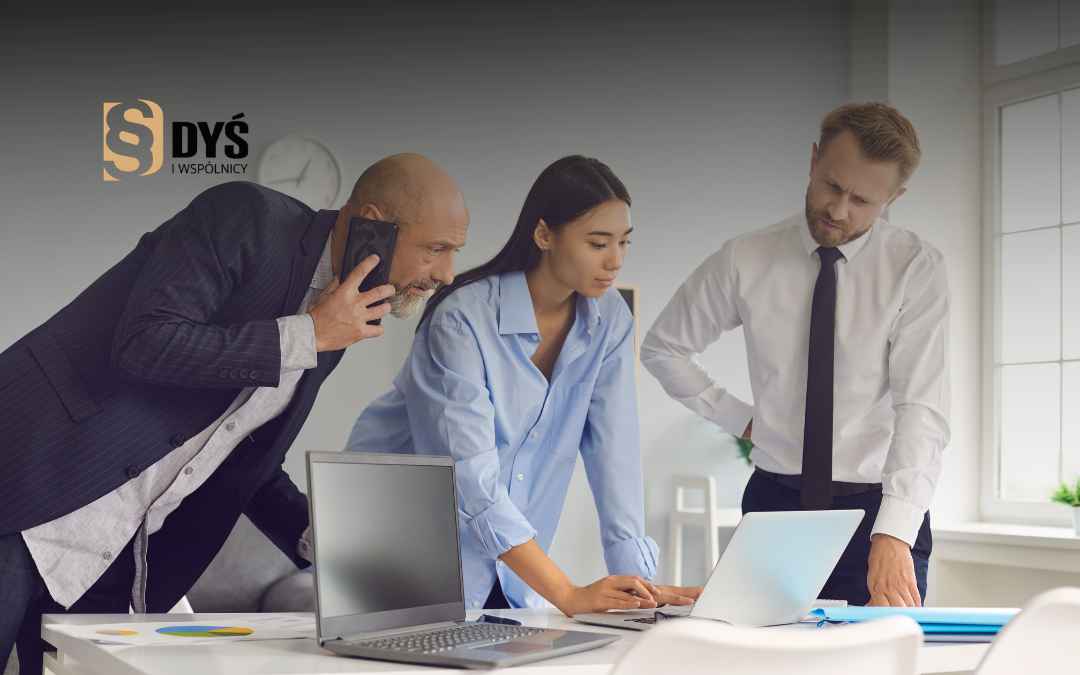 Zarząd i doradcy analizują dokumenty fuzji spółek na laptopie w biurze.