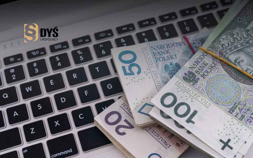 Polskie banknoty (20, 50, 100 zł) leżące na klawiaturze laptopa z logo kancelarii.